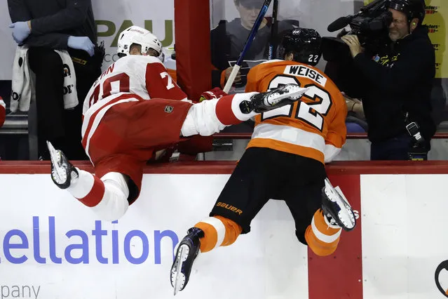 Detroit Red Wings' Christoffer Ehn, left, and Philadelphia Flyers' Dale Weise fly into the bench after a collision during the third period of an NHL hockey game, Tuesday, December 18, 2018, in Philadelphia. Philadelphia won 3-2. (Photo by Matt Slocum/AP Photo)