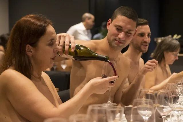 A nude diner fills wine for another at the newly opened nudist restaurant “o'naturel” in Paris on December 5, 2017. Leave your coats, your pants and your inhibitions at the door: a Paris restaurant has begun serving up classic French fare to diners in the nude. Located down a quiet side street in southwest Paris, O'naturel, billed as the French capital's first nudist restaurant, is the brainchild of 42-year-old twins Mike and Stephane Saada. (Photo by Geoffroy Van Der Hasselt/AFP Photo)