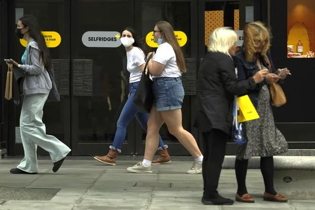 Two women walk along Oxford Street while wearing a face masks against the coronavirus in London, Friday, August 6, 2021. The number of covid positive tests for August 5, the latest available figure show the United Kingdom had just over 30,000 confirmed infections. (Photo by Alastair Grant/AP Photo)