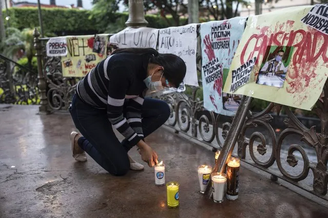 A woman lights a candle during a vigil to protest the murder of Mexican radio journalist Jacinto Romero, in Orizaba, Veracruz state, Mexico, Thursday, August 19, 2021. (Photo by Felix Marquez/AP Photo)