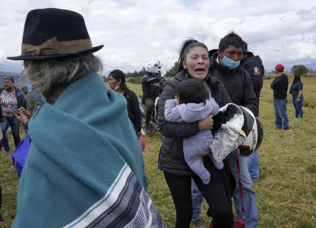A woman cries holding her child as she waits for news of her loved one held inside Latacunga jail after a deadly riot in Latacunga, Ecuador, Tuesday, October 4, 2022. A clash between inmates armed with guns and knives inside the prison has left at least 15 people dead and 20 injured. (Photo by Dolores Ochoa/AP Photo)