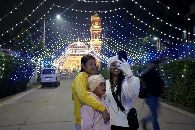 People take selfies in front of the decorated St. Joseph's Cathedral on the eve of Christmas in Prayagraj, India, Sunday, December 24, 2023. Although Christians comprise only two percent of the population Christmas is a national holiday and is observed across the country as an occasion to celebrate. (Photo by Rajesh Kumar Singh/AP Photo)