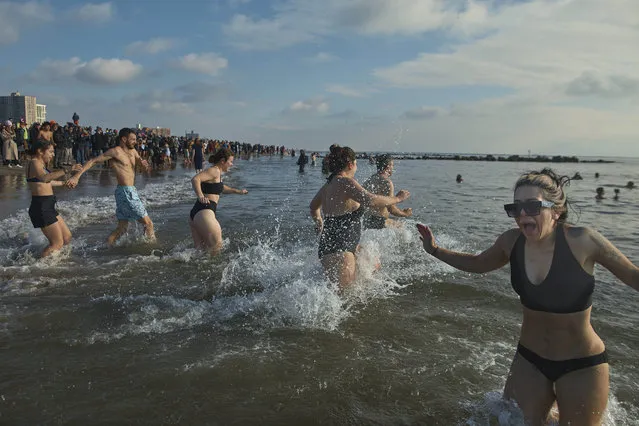 Revelers react as they enter the cold water during the annual Polar Bear Plunge on New Year's Day, Monday, January 1, 2024, in New York. (Photo by Andres Kudacki/AP Photo)