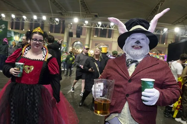 Darts fans dressed as characters from Alice in Wonderland get their drinks at the bar as they attend the quarterfinals of the World darts Championship at Alexandra Palace in London, Sunday, December 31, 2023. (Photo by Kin Cheung/AP Photo)