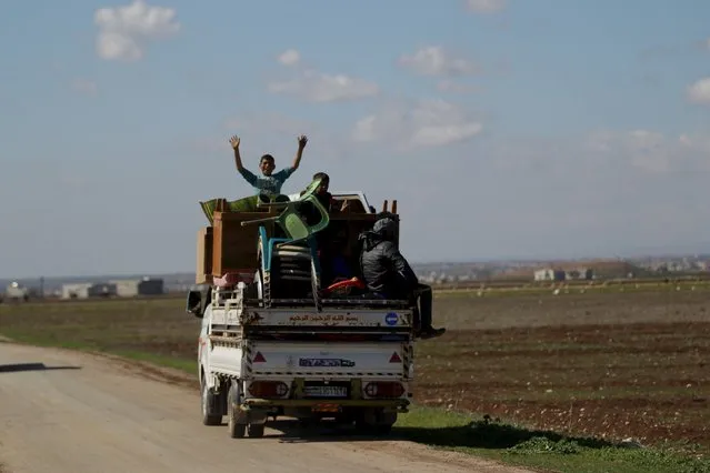 A boy gestures while riding with others a pick-up truck with their belongings in Tel Mamo village, in the southern countryside of Aleppo, Syria March 6, 2016. (Photo by Khalil Ashawi/Reuters)