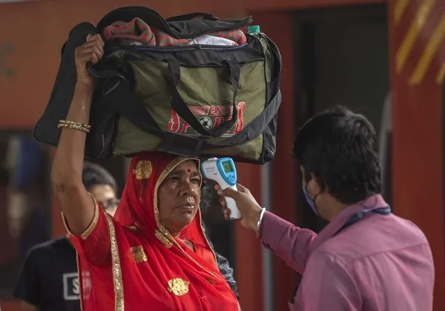 A health worker checks body temperature of a traveler as a precaution against the coronavirus before allowing her to proceed at train station in Mumbai, India, Thursday, September 30, 2021. (Photo by Rafiq Maqbool/AP Photo)