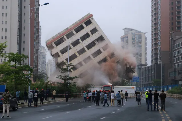 People watch the controlled demolition of an eight-storey “nail house” that stood on a road in Haikou, Hainan province, China on February 24, 2019. (Photo by Reuters/China Stringer Network)