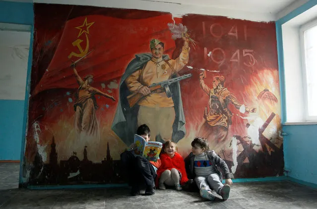 Children, who were recently evacuated from their residencies due to shelling, laugh while sitting in front of a wall painting commemorating the victory over Nazi Germany in World War Two at a dormitory in Donetsk, Ukraine, February 2, 2017. (Photo by Alexander Ermochenko/Reuters)