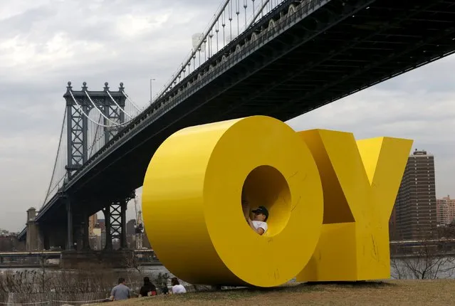 A person sits inside the 'OY/YO' sculpture, designed by artist Deborah Kass, at the Brooklyn Bridge Park in New York March 10, 2016. (Photo by Shannon Stapleton/Reuters)