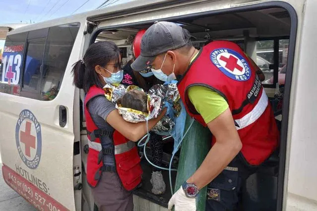 In this February 9, 2024 handout photo provided by the Philippine Red Cross, rescuers provide medical attention to a child at a hospital in Mawab, Davao de Oro province, after her rescue at the landslide-hit village of Maco, Davao de Oro province, southern Philippines. Several villagers remain missing while some bodies have been recovered from underneath the rubble as rescue efforts continue at the landslide-hit area. (Photo by Philippine Red Cross via AP Photo)