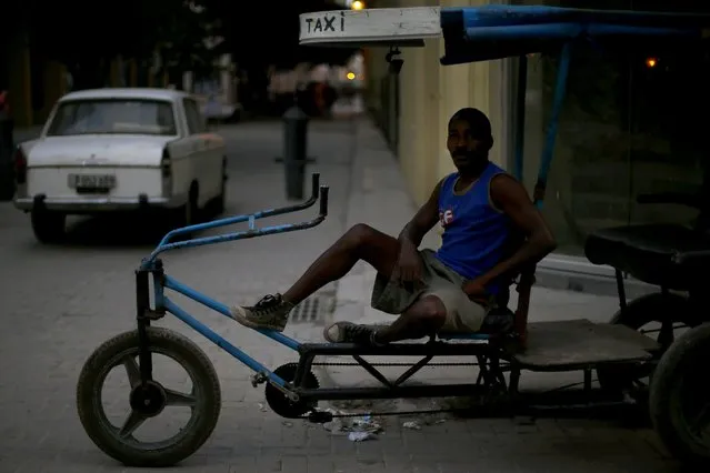 A man sits on his taxi-bike on a street at Havana city, Cuba, March 17, 2016. (Photo by Ivan Alvarado/Reuters)