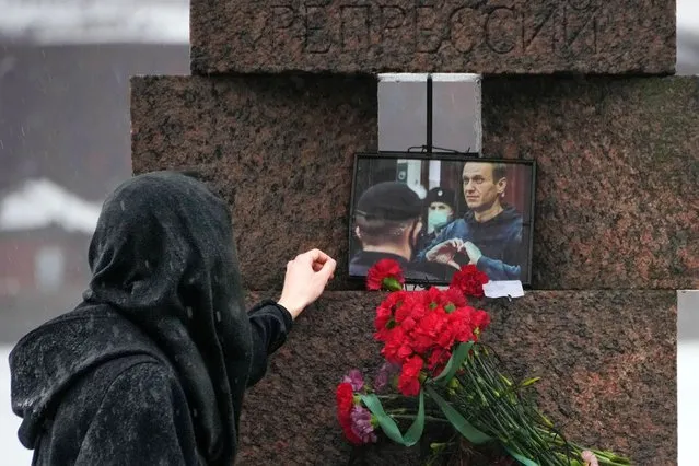 A woman touches a photo of Alexei Navalny after laying flowers paying the last respect to him at the Memorial to Victims of Political Repression in St. Petersburg, Russia on Saturday, February 17, 2024. Russian authorities say that Alexei Navalny, the fiercest foe of Russian President Vladimir Putin who crusaded against official corruption and staged massive anti-Kremlin protests, died in prison. He was 47. (Photo by Dmitri Lovetsky/AP Photo)