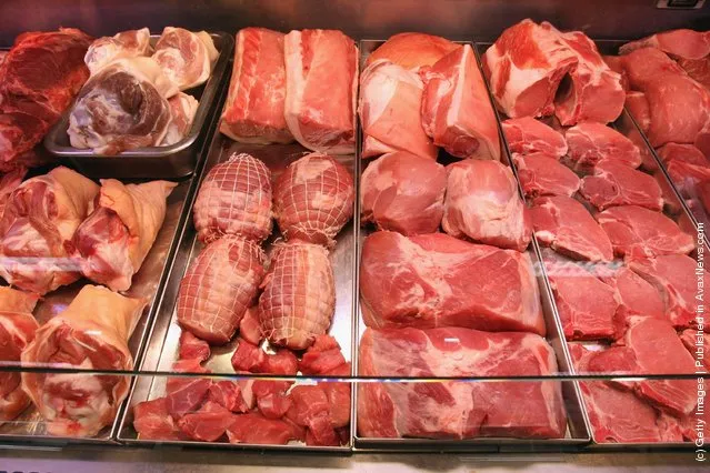 Cuts of beef and pork lie in a display counter at a supermarket