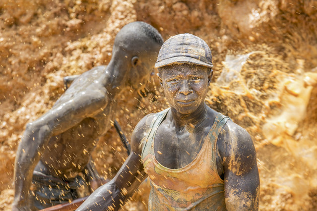Two mud covered miners work in the blistering sun in Ghana, West Africa, 2014. (Photo by Heidi Woodman/Barcroft Images)