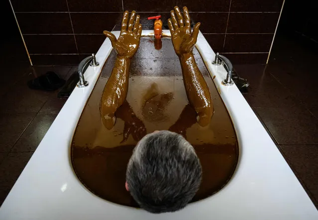 A man bathes in a tub filled with Naftalan crude oil during a treatment session at Sehirli Naftalan Health Center, some 300 kilometres (186 miles) from capital Baku, on March 21, 2019. Immersed up to her neck in crude oil, a Russian woman suffering from joint disease smiles in delight, confident that the treatment at a spa in northwestern Azerbaijan will cure her painful condition. (Photo by Mladen Antonov/AFP Photo)