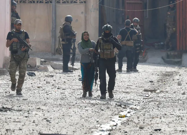 A woman walks with an Iraqi special forces soldier after she crossed from Islamic State controlled part of Mosul to Iraqi troops controlled part of Mosul, Iraq March 1, 2017. (Photo by Goran Tomasevic/Reuters)