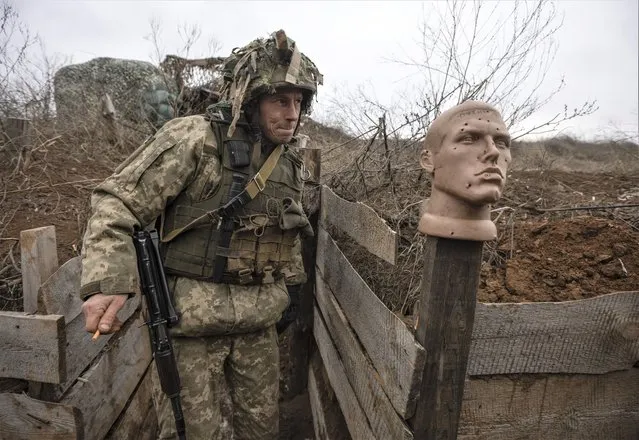 A Ukrainian soldier walks in a trench at the line of separation from pro-Russian rebels, Donetsk region, Ukraine, Sunday, January 9, 2022. President Joe Biden has warned Russia's Vladimir Putin that the U.S. could impose new sanctions against Russia if it takes further military action against Ukraine. (Photo by Andriy Dubchak/AP Photo)