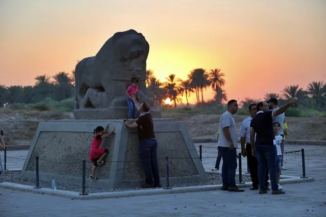 People stand near the Lion of Babylon at the archaeological site of Babylon, Iraq, Friday, July 5, 2019. Iraq on Friday celebrated the UNESCO World Heritage Committee's decision to name the historic city of Babylon a World Heritage Site in a vote held in Azerbaijan's capital, years after Baghdad began campaigning for the site to be added to the list. (Photo by Anmar Khalil/AP Photo)