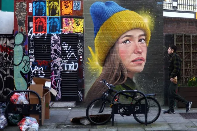 A man walks past a mural in support of Ukraine by artist WOSKerski, as Russia's invasion of Ukraine continues, in London, Britain, March 14, 2022. (Photo by Hannah McKay/Reuters)