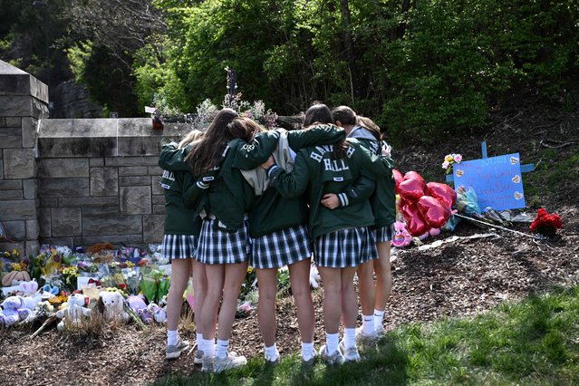Girls embrace in front of a makeshift memorial for victims by the Covenant School building at the Covenant Presbyterian Church following a shooting, in Nashville, Tennessee, March 28, 2023. A heavily armed former student killed three young children and three staff in what appeared to be a carefully planned attack at a private elementary school in Nashville on Monday, before being shot dead by police Chief of Police John Drake named the suspect as Audrey Hale, 28, who the officer later said identified as transgender. (Photo by Brendan Smialowski/AFP Photo)