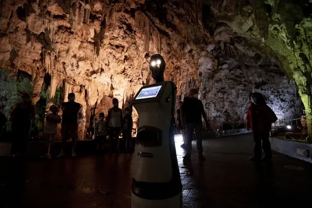 Persephone guides the visitors inside Alistrati cave, about 135 kilometers (84 miles) northeast of Thessaloniki, Greece, Monday, August 2, 2021. Persephone, billed as the world's first robot used as a tour guide inside a cave, has been welcoming visitors to the Alistrati cave, since mid-July. (Photo by Giannis Papanikos/AP Photo)