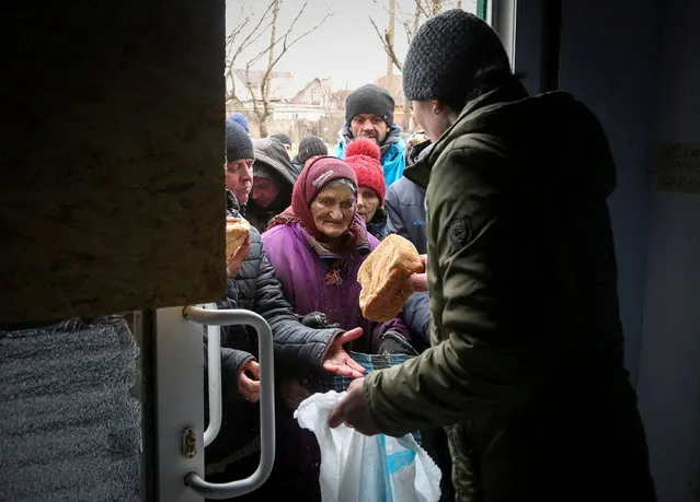 Local residents receive bread during a humanitarian aid distribution amid ongoing fighting in Ukraine-Russia conflict in the besieged southern port city of Mariupol, Ukraine on April 4, 2022. (Photo by Chingis Kondarov/Reuters)