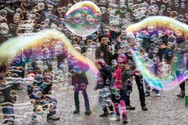 Visitors and children play with big and small bubbles in Cologne, Germany, 03 January 2016. The weather in Germany is divided between mild temperatures in the south-west, where as the north of the country is being subject to Siberian cold air. (Photo by Maja Hitij/EPA)