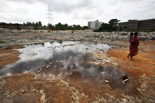 An Indian walks past contaminated water at the landfill at Vijyaipura, on the outskirts of Bangalore, India, 20 July 2015. According to reports tonnes of solid waste and electronic e-waste dumped every day over the years by Bruhat Bengaluru Mahanagara Palike (BBMP) and other agencies at the landfill area has led to the deaths of everal cows and pet animals with many more suffering a wide range of infectious and chronic illnesses. (Photo by Jagadeesg N.V./EPA)