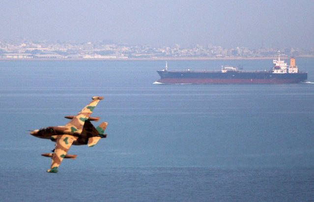 An Iranian military fighter plane flies past an oil tanker during naval manoeuvres in the Gulf and Sea of Oman April 5, 2006. (Photo by Fars News/Reuters)