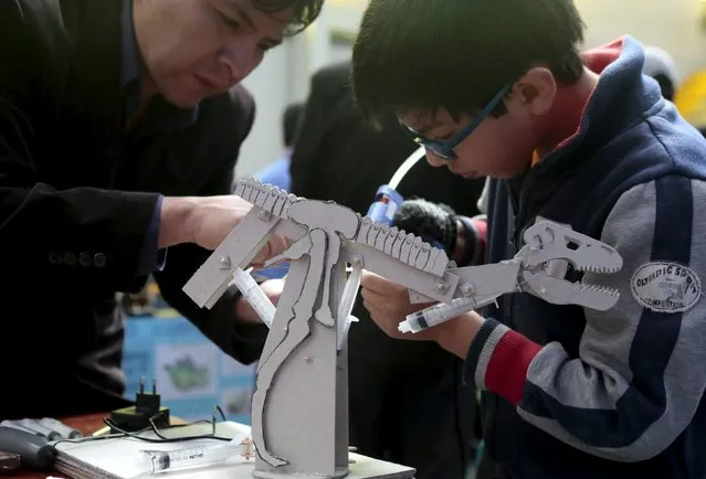 A student is helped by his teacher to build a dinosaur robot during the annual robotics fair supported by the Bolivian Education Ministry in La Paz, August 10, 2015. (Photo by David Mercado/Reuters)