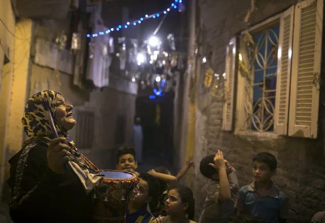 In this Monday, June 12, 2017 photo, Hajja Dalal, a 43-year-old “mesaharati”, or dawn caller, wakes people up for a meal before sunrise, during the Islamic holy month of Ramadan, in the Ard Besary district in Cairo, Egypt. Each night, Dalal, banging her decorated drum, chants traditional religious phrases and calls out to residents' children by name to wake them in time for the vital pre-dawn meal known as “suhour”. (Photo by Amr Nabil/AP Photo)