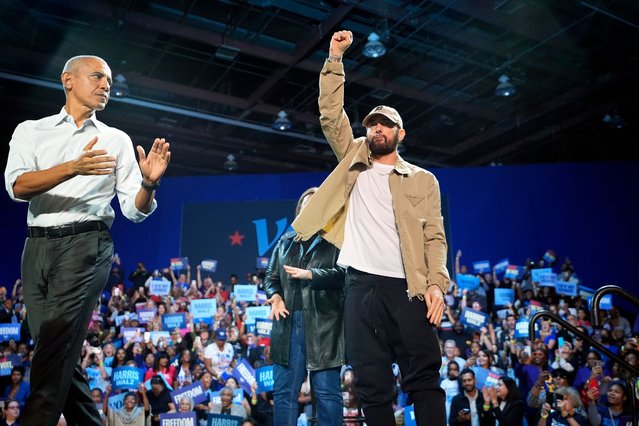 Rapper Eminem, center, greets the crowd on stage with former President Barack Obama, left, at a campaign rally supporting Democratic presidential nominee Vice President Kamala Harris, Tuesday, October 22, 2024, in Detroit. (Photo by Paul Sancya/AP Photo)