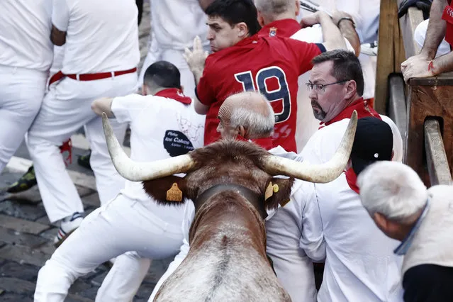 People take part in the traditional Running of the Bulls during the San Fermin Festival in Pamplona, Navarra, Spain, 07 July 2022. Pamplona's Running of the Bulls, known locally as Sanfermines, resumed after a two-year hiatus due to the coronavirus disease (COVID-19) pandemic. The bull-running fiesta is held annually from 06 to 14 July in commemoration of the city's patron saint. Visitors from all over the world attend the festival. Many of them physically participate in the highlight event – the running of the bulls, or encierro – where they attempt to outrun the animals along a route through the narrow streets of Pamplona's old city. (Photo by Jesús Diges/EPA/EFE)
