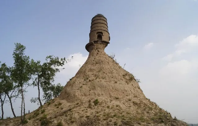 An ancient tower is seen balancing on the top of a dirt hill, with its base slightly eroded, along a grassland in Qixian county, Shanxi province July 19, 2014. Local authorities said they were looking into way to protect and remedy the tower after pictures, taken by a relic preservation enthusiast, were posted on the Internet, local media reported. (Photo by Reuters/Stringer)