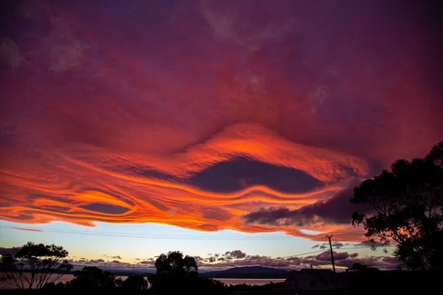 Wayne Painter, 70, saw the sun set beneath lenticular clouds 20km wide in Tasmania, Australia in November 2021. Some likened the image to a near-miss with Mars. (Photo by Wayne Painter/Kennedy News)