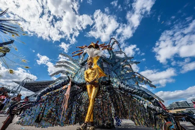 A parade participant dressed in gold clothing pulls along a large peacock-shaped float behind him during the festival in Exhibition Place in Toronto, Canada on July 30, 2022. Following two years of lockdown from the covid-19 pandemic, the Toronto Caribbean Carnival returns with the Grand Parade. (Photo by Katherine Cheng/SOPA Images/LightRocket via Getty Images)