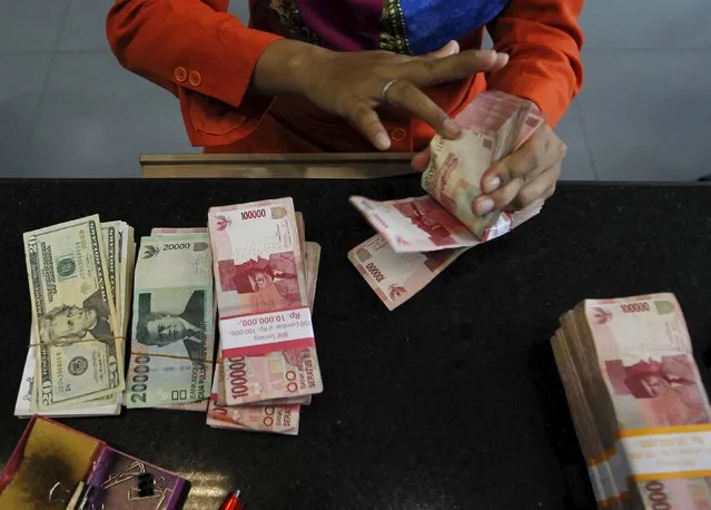 A teller counts Indonesian rupiah notes and U.S. dollars for a customer at a money changer in Jakarta, Indonesia, August 26, 2015. Indonesia's central bank has urged exporters and businesses not to hoard foreign currency as part of its effort to maintain financial stability as the rupiah hit a 17-year low versus the dollar. (Photo by Nyimas Laula/Reuters)