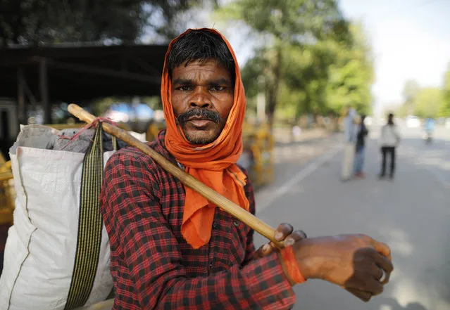 Hiralal, a daily wage laborer, leaves for his village as the city comes under lockdown in Prayagraj, India , Thursday, March 26, 2020. Some of India's legions of poor and people suddenly thrown out of work by a nationwide stay-at-home order began receiving aid distribution Thursday, as both the public and private sector work to blunt the impact of efforts to curb the coronavirus pandemic. Untold numbers of them are now out of work and many families have been left struggling to eat. (Photo by Rajesh Kumar Singh/AP Photo)