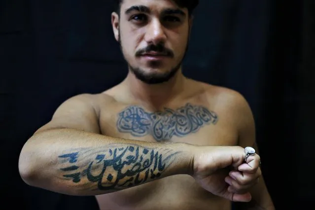 In this Monday, July 18, 2016 photo, Alodi Issa, 22, poses for a photo showing off his tattoos with Shiite Muslim religious slogans in the southern suburb of Beirut, Lebanon. The tattoo in Arabic reads, “Oh, the revenge for Hussein. Ali, Fatima. 313, Oh Abu Fadel al-Abbas”. (Photo by Hassan Ammar/AP Photo)