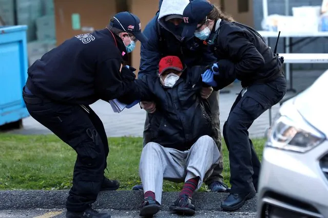 Paramedics move a man to an ambulance after he collapsed while waiting in line during a food rescue operation run by City Harvest during the outbreak of the coronavirus disease (COVID-19) in the Bronx borough of New York City, New York, U.S., April 22, 2020. (Photo by Mike Segar/Reuters)