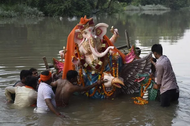 Hindu devotees immerse an idol of the elephant-headed Hindu God Ganesha in a river during the ten-day-long “Ganesh Chaturthi” festival on the outskirts of Amritsar on September 2, 2022. (Photo by Narinder Nanu/AFP Photo)