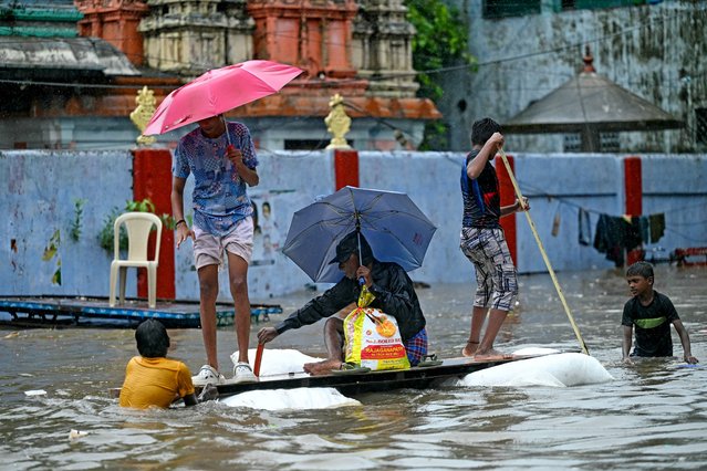 People make their way through a flooded street amid heavy rainfall in Chennai on October 15, 2024. (Photo by R Satish Babu/AFP Photo)
