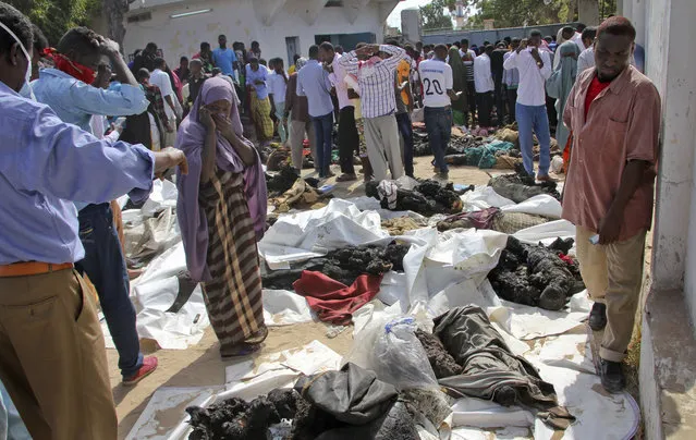 A Somali woman reacts as she stands by the remains of victims of Saturday's blast, in Mogadishu, Somalia, Sunday, October 15, 2017. The death toll from the most powerful bomb blast witnessed in Somalia's capital rose Sunday to at least 189 with more than 200 injured, making it the deadliest single attack ever in the Horn of Africa nation, police and hospital sources said. (Photo by Farah Abdi Warsameh/AP Photo)