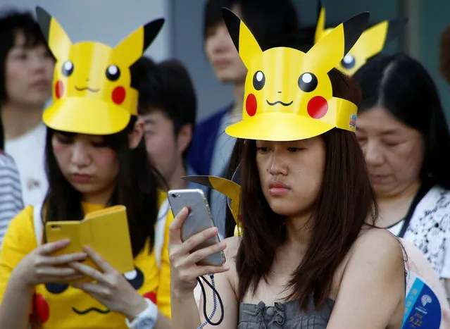 People wearing 'Pikachu' hats use mobile phones before the parade by performers wearing Pokemon's character Pikachu costumes in Yokohama, Japan, August 7, 2016. (Photo by Kim Kyung-Hoon/Reuters)