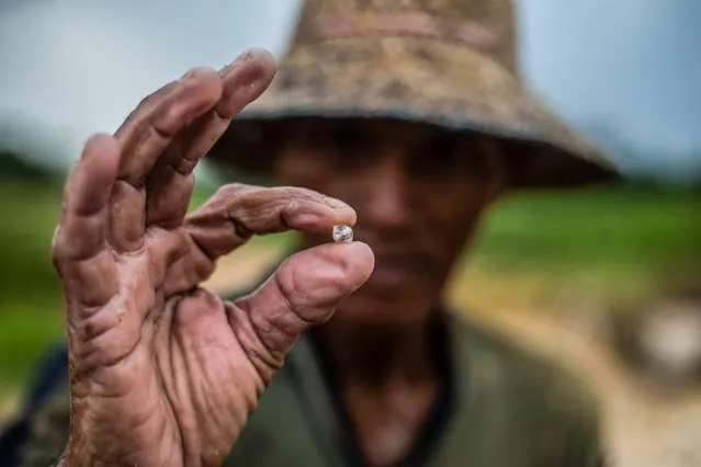 A traditional miner shows a raw diamond found during a sieving process at Cempaka village in Banjarbaru on September 29, 2022. (Photo by Aditya Aji/AFP Photo)