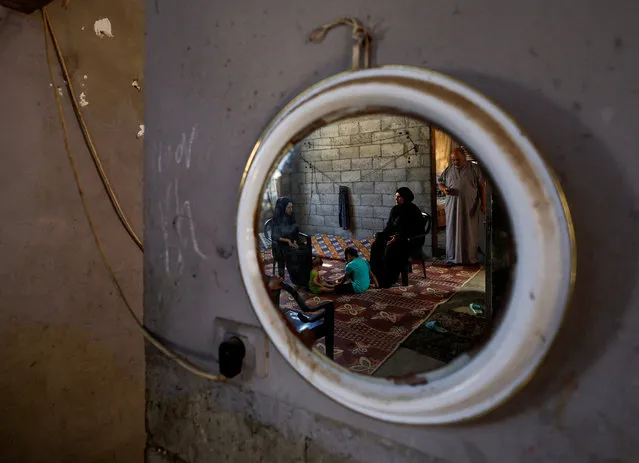 Family of Shadi Khail, who was killed in the recent Israel-Gaza fighting, are refelcted in a mirror as they sit inside their home in Gaza City on August 16, 2022. (Photo by Mohammed Salem/Reuters)