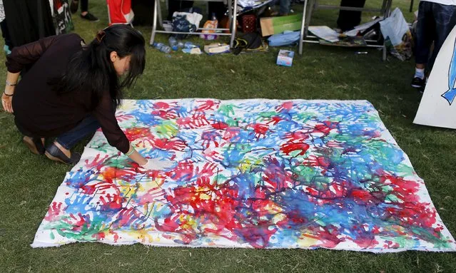 A women makes handprint art during a festival commemorating the International Day of Peace in Baghdad, September 21, 2015. (Photo by Thaier al-Sudani/Reuters)