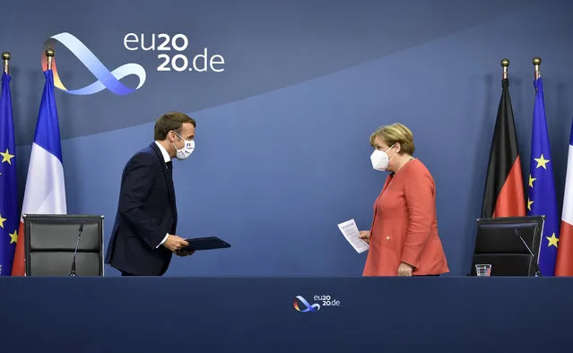 German Chancellor Angela Merkel, right, and French President Emmanuel Macron prepare to address a media conference at the end of an EU summit in Brussels, Tuesday, July 21, 2020. Weary European Union leaders finally clinched an unprecedented budget and coronavirus recovery fund early Tuesday, finding unity after four days and as many nights of fighting and wrangling over money and power in one of their longest summits ever. (Photo by John Thys/Pool Photo via AP Photo)