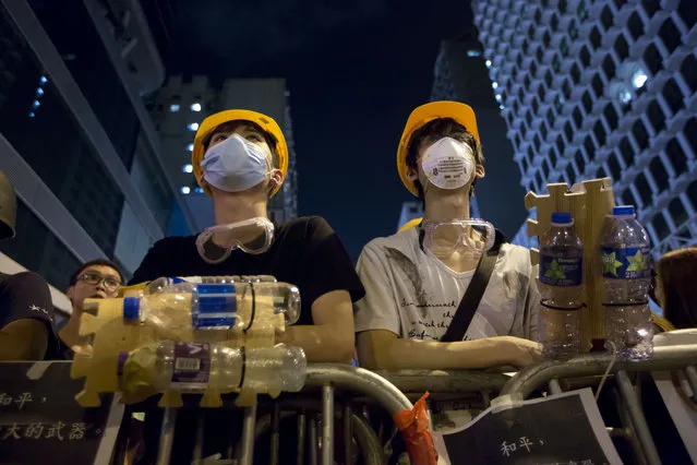 Protesters wear protective gear made by plastic bottle at a barricade in the Mong Kok district of Hong Kong, early Monday, October 20, 2014. Three weeks ago, students at a rally stormed a fenced-off courtyard outside Hong Kong's government headquarters, triggering unprecedented mass protests for greater democracy in the semiautonomous Chinese city. (Photo by Kin Cheung/AP Photo)