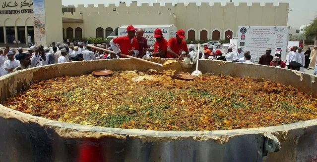 Omani men stir ingredients in a large pot as they prepare a traditional “Kabsa” dish in an attempt to set a new Guinness world record in Muscat on July 23, 2010. (Photo by Mohammed Mahjoub/AFP Photo)